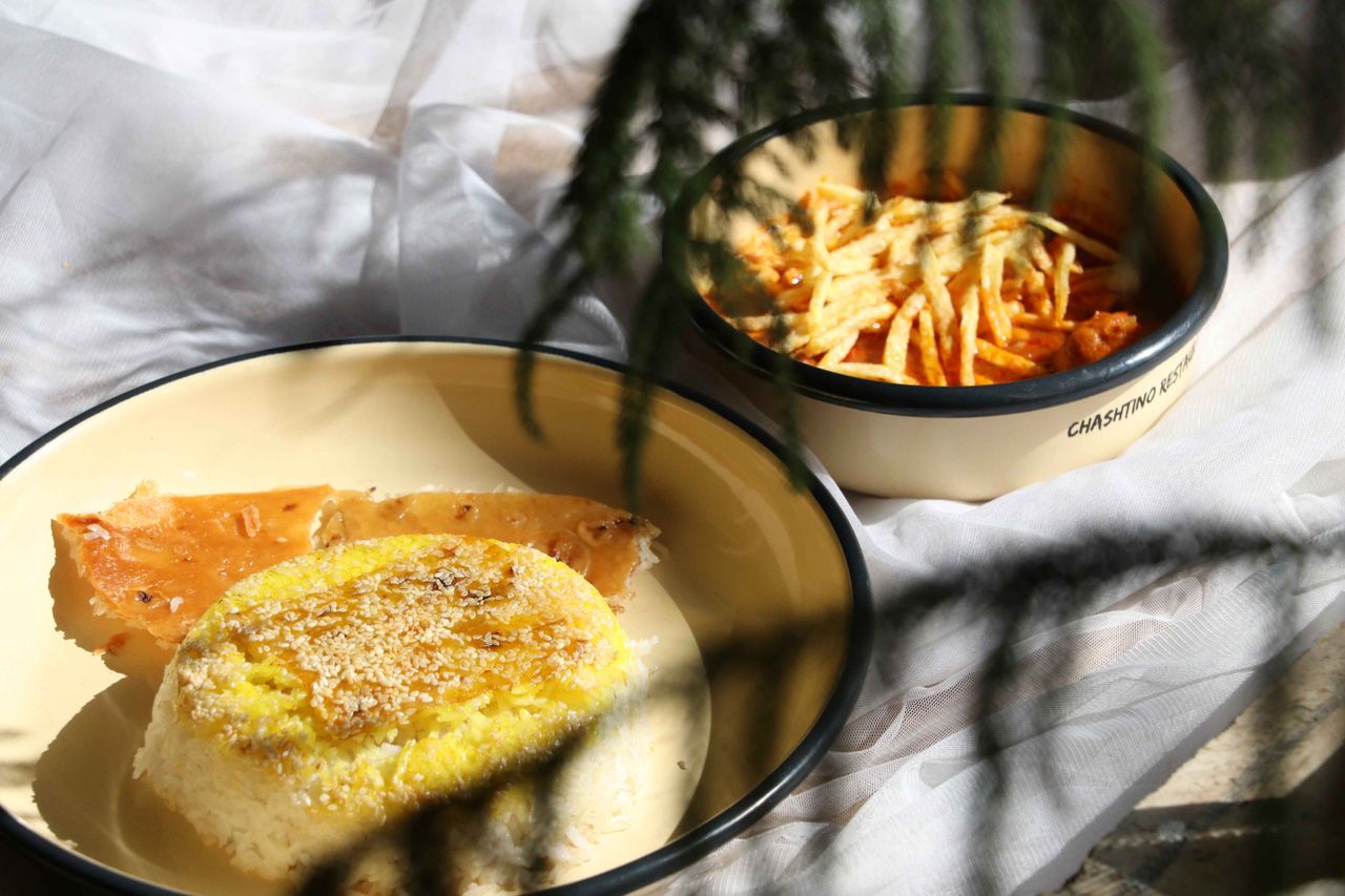 heros-img Authentic Persian meal featuring Gheimeh stew and crispy tahdig, perfect in natural light.