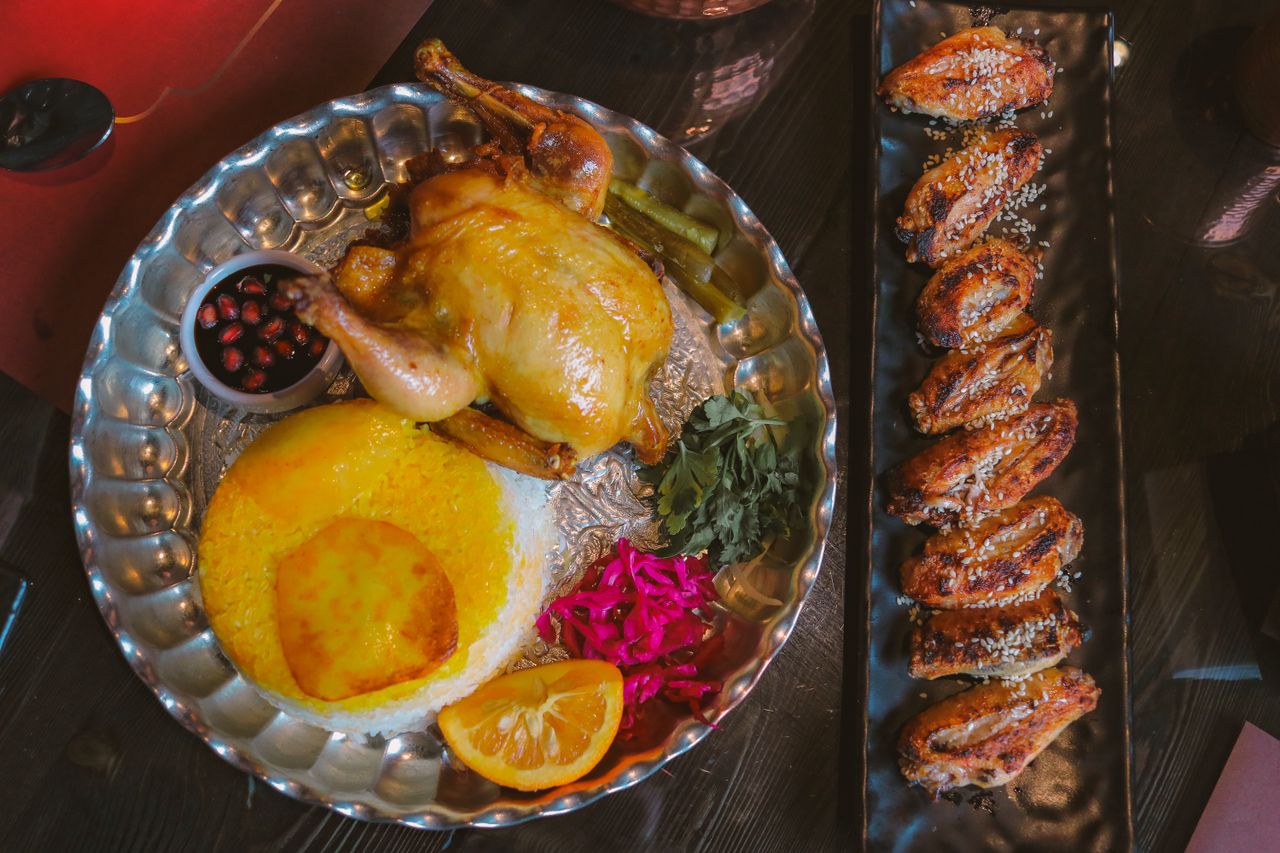 about-us-02 A gourmet Persian meal featuring roast chicken, saffron rice, and assorted sides. Ideal for foodies.